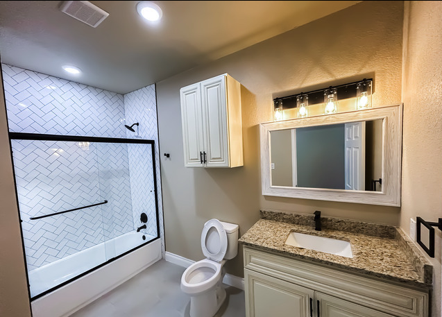 Full bath with herringbone-tile shower and granite vanity